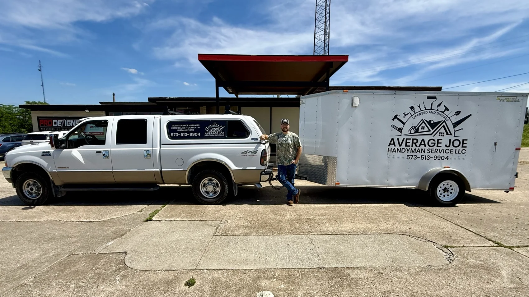 Josias standing between his work truck and branded enclosed tool trailer